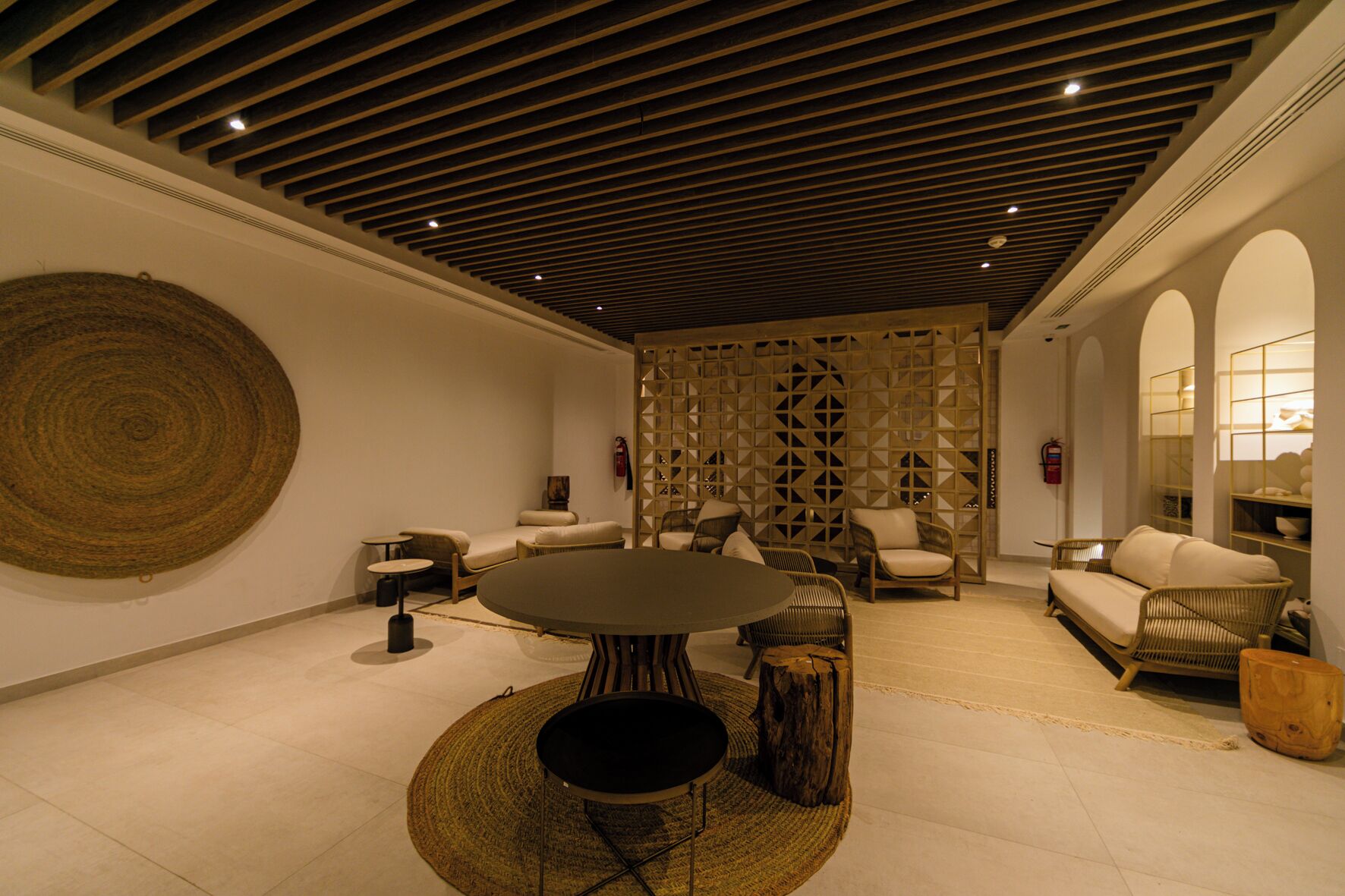 A modern interior with a round table, sofas, and a decorative wall.
