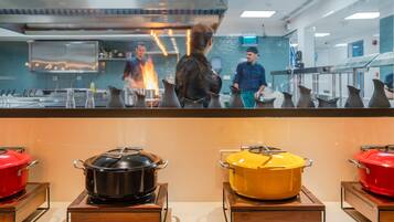A kitchen area with pots on display, a chef in the background, and a counter with a menu.