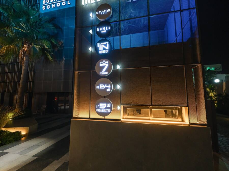Un bâtiment dont l’enseigne lumineuse indique « The NING Hospitality Business School » et « 8 Hotel Business School ».