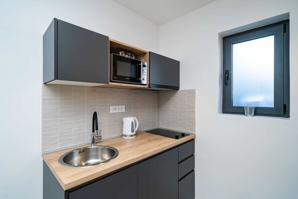 A modern kitchen with a built-in microwave, a stainless steel sink, and a window above the sink.