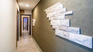 A hallway with a textured wall, a checkered floor, and a door leading to a bathroom.