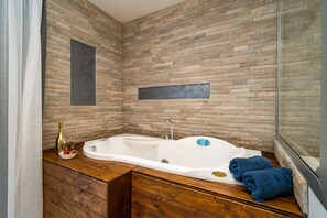 A modern bathroom with a wooden vanity, a freestanding bathtub, and a glass shower enclosure.