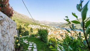 A stone pathway leading to a hillside with a view of a town and mountains in the distance.