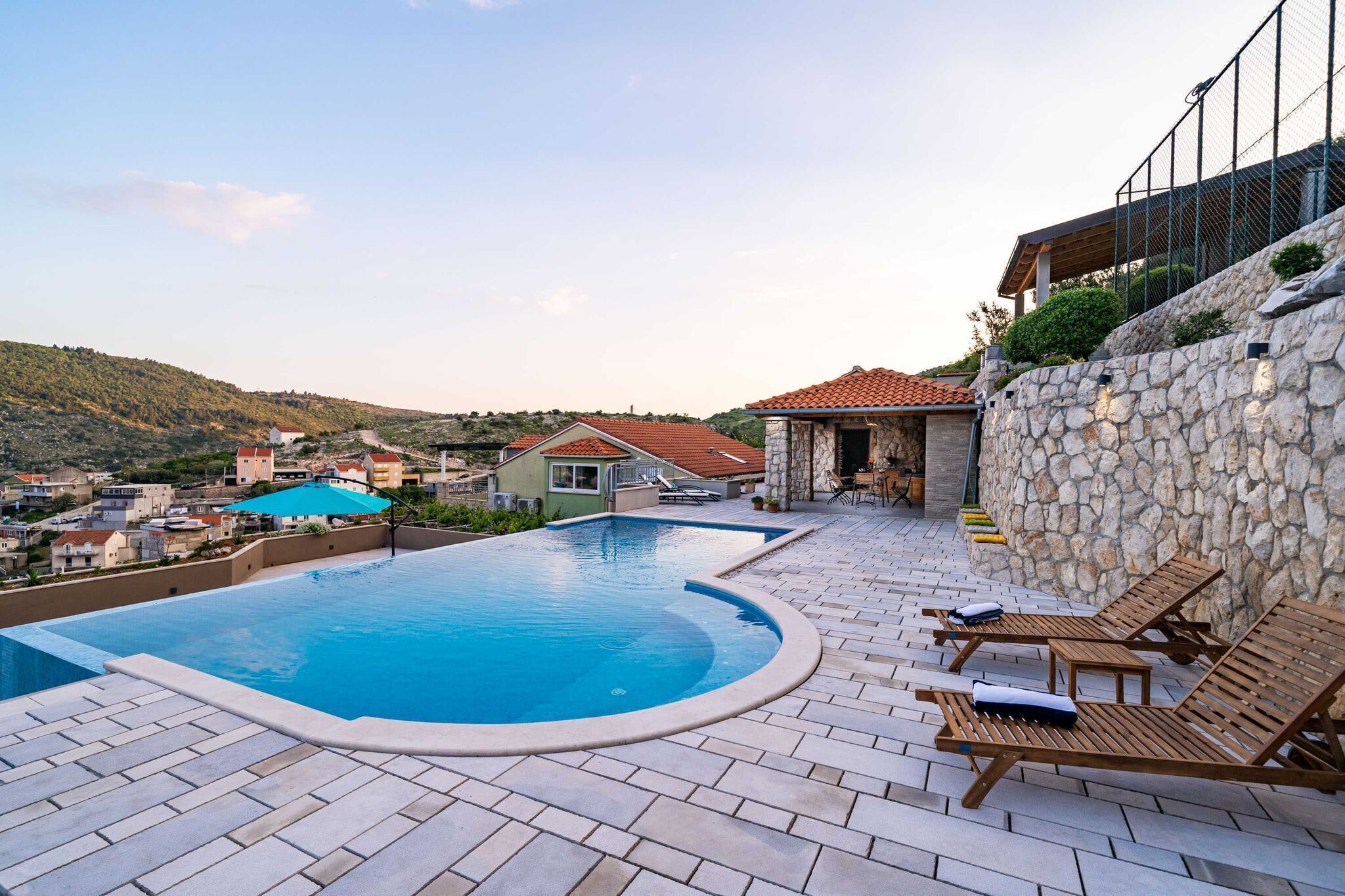 Una piscina con sillones de descanso y una pared de piedra.