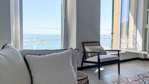 A room with a sofa and a chair facing a balcony with a view of the sea. - Mareviglia - Meereswunder by Interhome (Imperia)