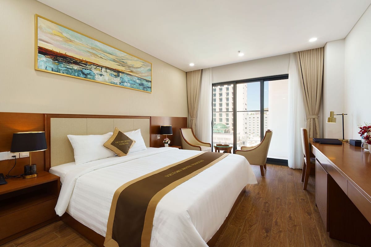 Une chambre d’hôtel avec un grand lit, un bureau, une chaise et un tableau au mur.