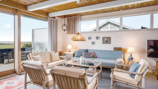 Amplia sala de estar con un ventanal grande, muebles de mimbre y vistas al exterior.