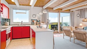 Cocina moderna con armarios rojos, una isla grande y un comedor con vistas.