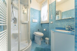A bathroom with a glass-enclosed shower, a toilet, a sink, and a mirror. - Leandro's House (Montecatini Terme)