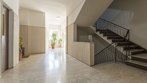 A spacious hallway with a staircase leading to an upper floor, featuring a modern design with light-colored walls and a marble floor. - Leandro's House (Montecatini Terme)
