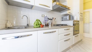 A modern kitchen with white cabinets, stainless steel appliances, and a tiled backsplash. - Leandro's House (Montecatini Terme)