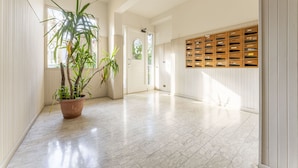 A hallway with a potted plant, a wooden storage unit, and a door leading to another room. - Leandro's House (Montecatini Terme)