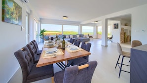 A spacious dining area with a long wooden table set for a meal, surrounded by comfortable seating. - Villa Bella Vista in Tribulje (Dobrinj)