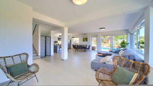 A spacious living area with a dining table, sofas, and wicker chairs. - Villa Bella Vista in Tribulje (Dobrinj)