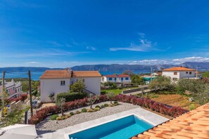 A residential area with a swimming pool, houses with red-tiled roofs, and a view of the sea and mountains. - Holiday House Villa Andro (Krk)
