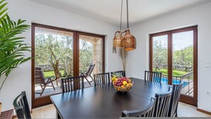 A dining area with a dark wooden table, black chairs, and a woven light fixture. - Holiday House Casa D Oro (Malinska-Dubasnica)