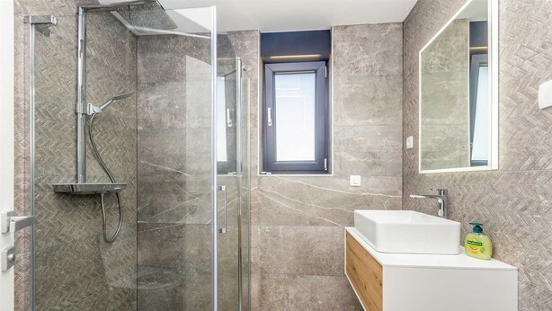 Une salle de bain moderne avec une douche à parois de verre, un lavabo blanc et un meuble-lavabo en bois.