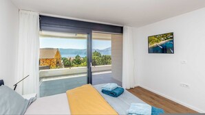 Une chambre d’hôtel avec un lit, une vue sur un balcon et un tableau accroché au mur.