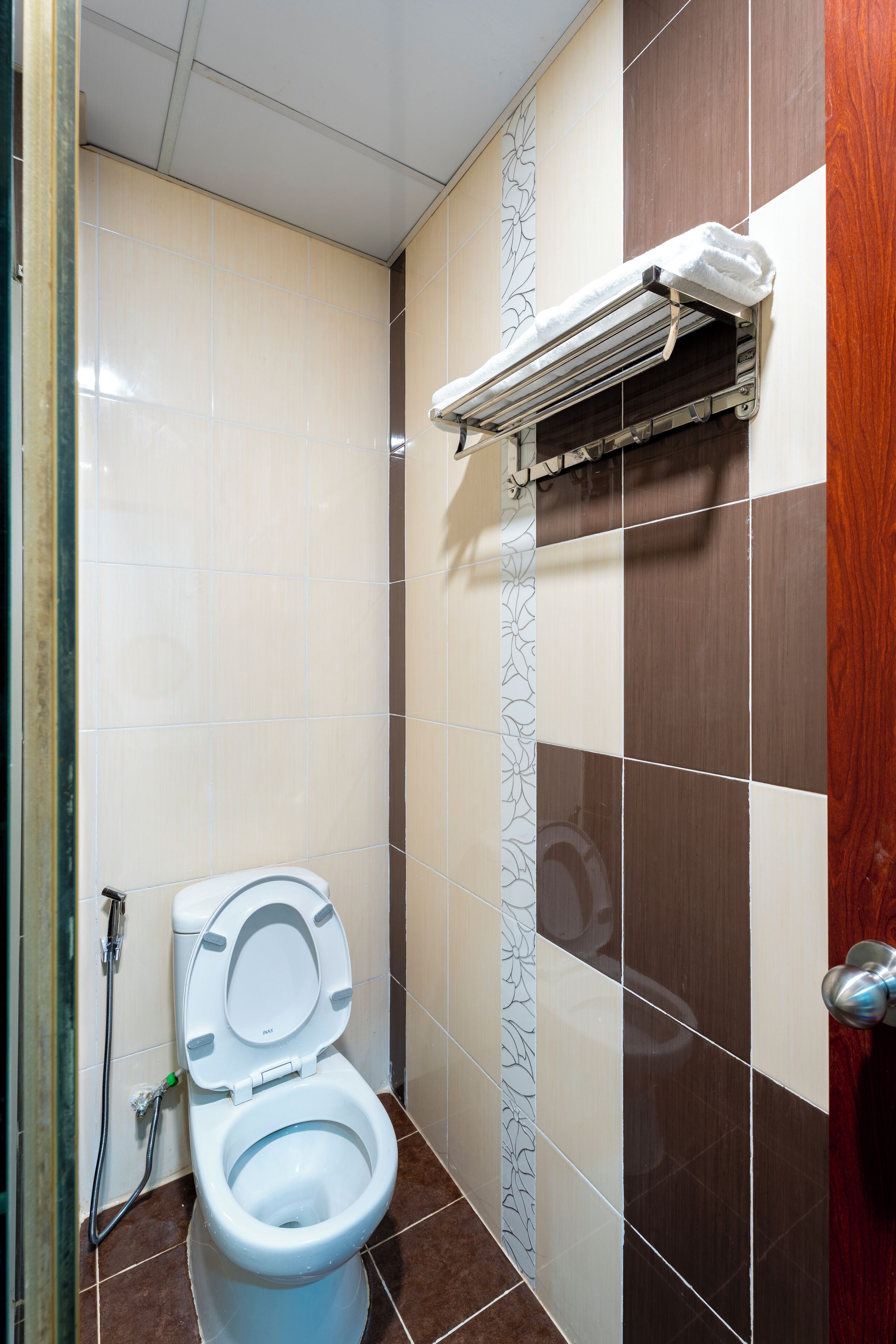 Un baño con inodoro, secamanos y equipo de aire acondicionado instalado en la pared.