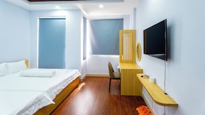 Een moderne hotelkamer met een bed, een bureau, een stoel en een televisie.