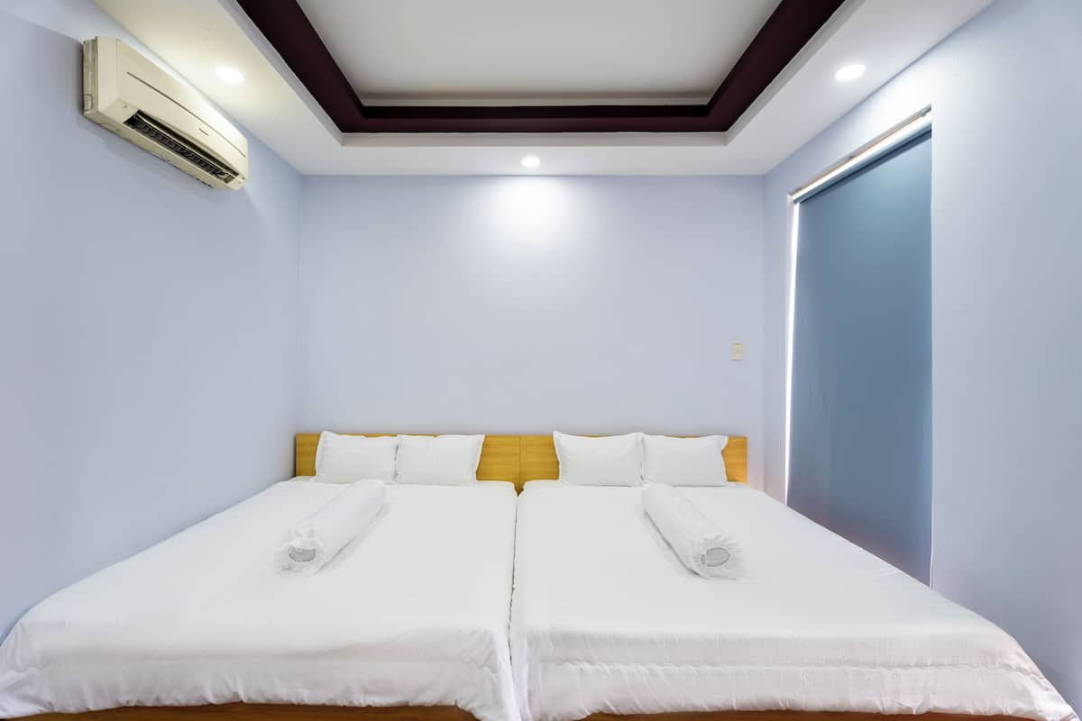 A double bed with white linens, a wooden headboard, and an air conditioning unit on the wall.