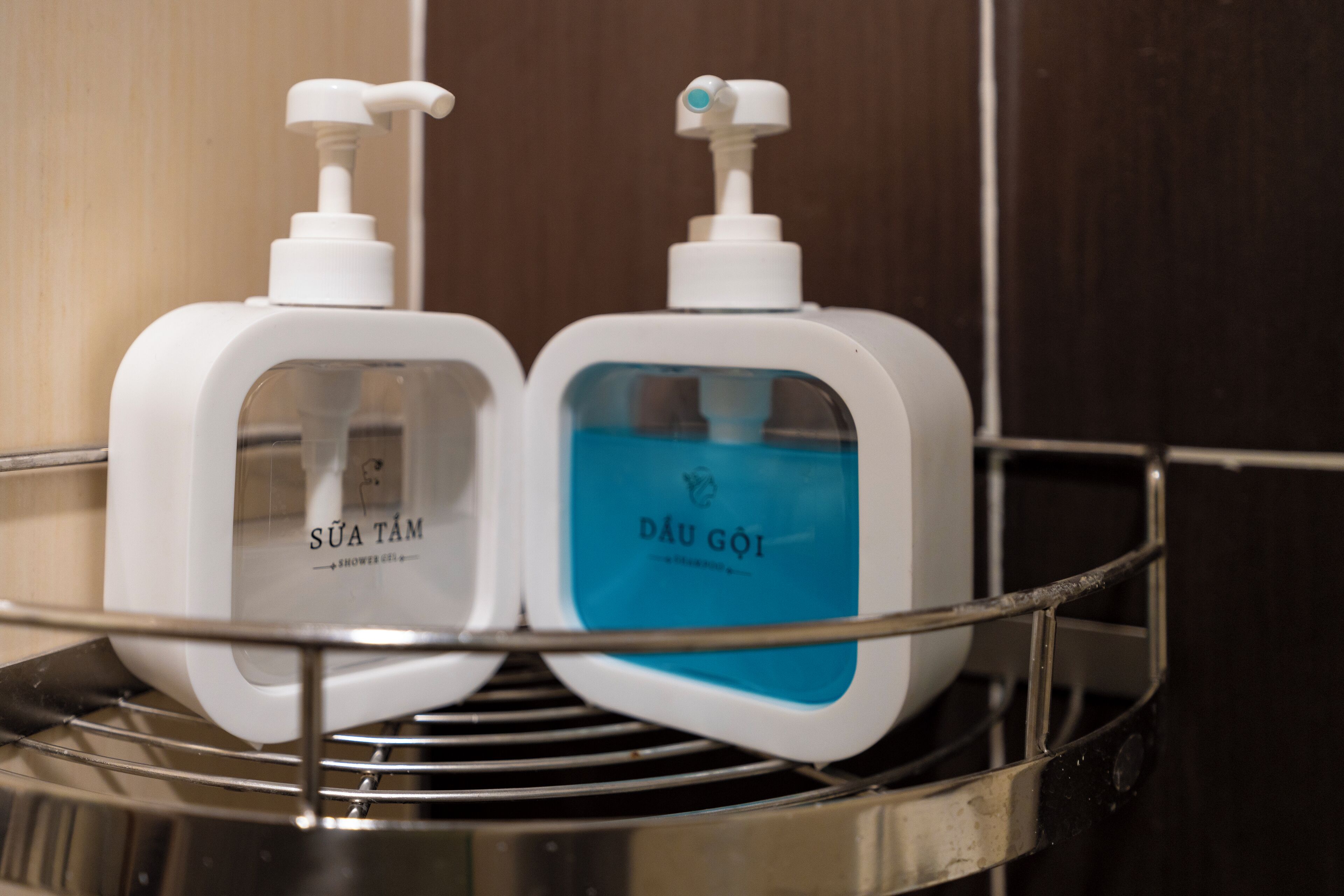 Two toiletry bottles on a metal shelf in a bathroom.