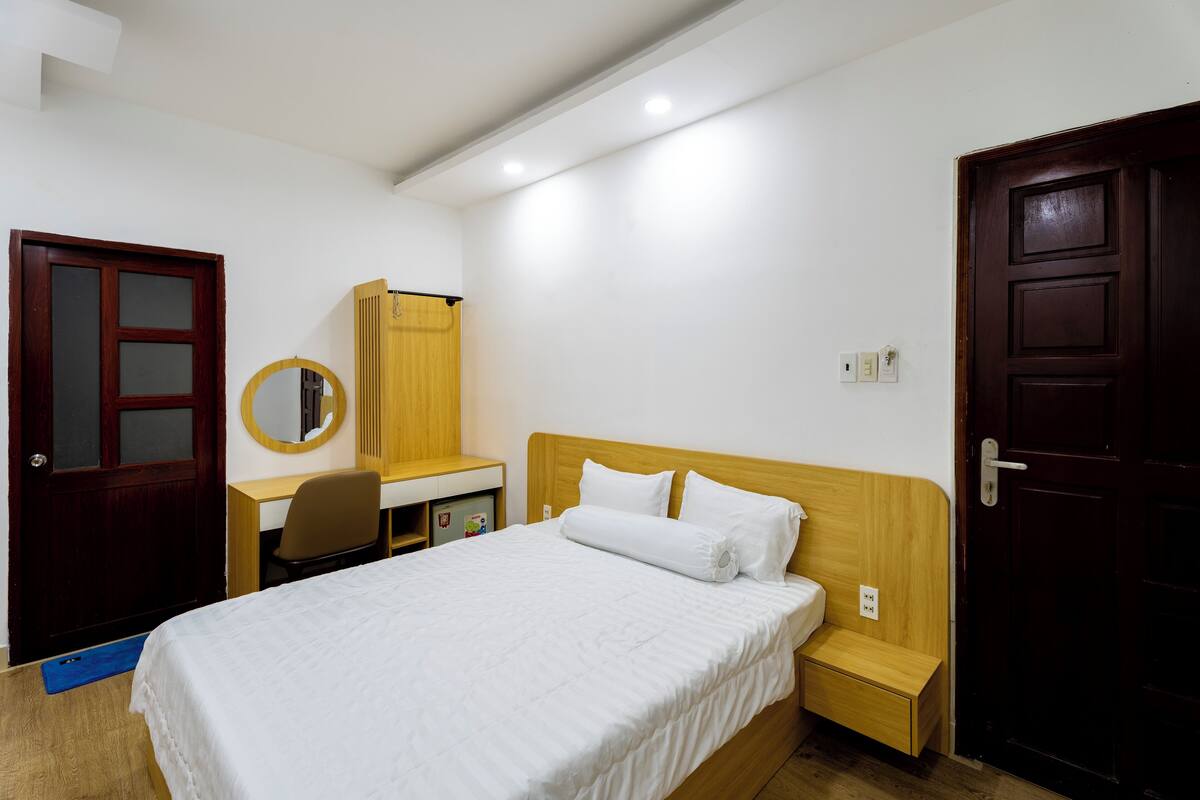 A neatly arranged bedroom with a bed, a desk, a chair, and a wardrobe.