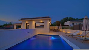 A modern outdoor pool area with a built-in hot tub, lounge chairs, and ambient lighting. - Villa Quarnaro With Heated Pool (Omisalj)