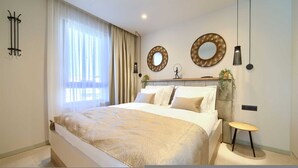 A modern bedroom with a large bed, two wall-mounted mirrors, a bedside table, and a hanging light fixture. - Villa Quarnaro With Heated Pool (Omisalj)