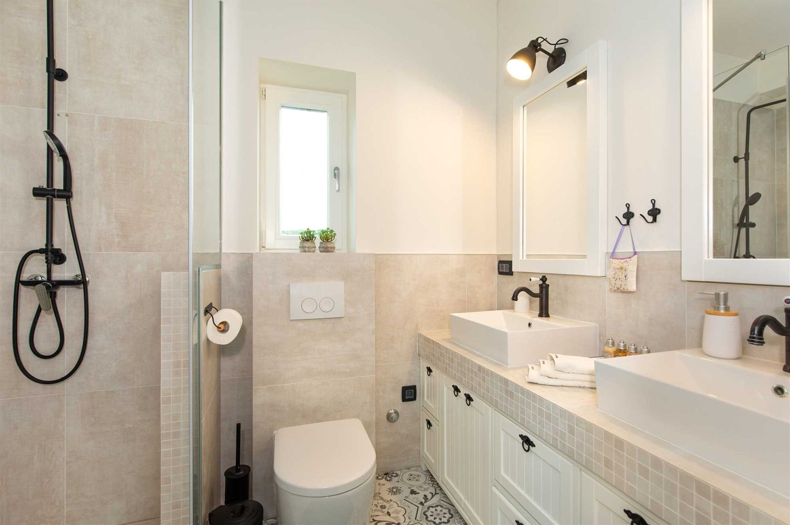 A modern bathroom with a shower, toilet, sink, and mirror.