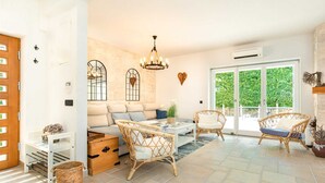 A bright living room with a sofa, wicker chairs, a coffee table, and a chandelier. - Villa Gita in Malinska (Malinska-Dubasnica)