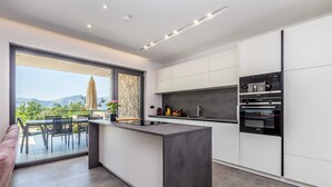 A modern kitchen with a central island, a dining area with a view, and built-in appliances. - Villa Verena With Heated Pool (Krk)