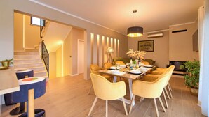 A modern dining area with a wooden table, yellow chairs, and a pendant light. - Villa Magnifica in Pinezici (Krk)
