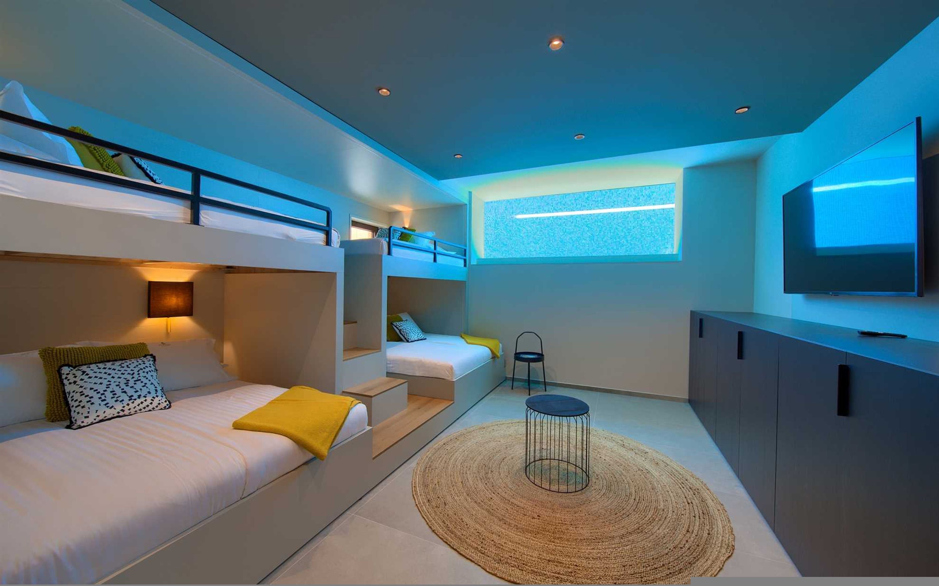 Une chambre moderne et compacte, dotée de lits superposés, d’un téléviseur à écran plat et d’un petit coin salon.