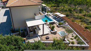 A villa with a swimming pool, outdoor seating, and a view of the sea. - Villa Lady With Heated Pool Jacuzzi and Sauna (Krk)