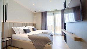 A modern hotel room with a large bed, a bedside table, a TV mounted on the wall, and a balcony with curtains. - Villa Lord With Heated Pool Jacuzzi and Sauna (Krk)