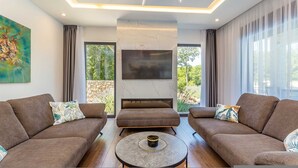 A modern living room with two sofas, a coffee table, a TV, and a fireplace. - Villa Meraviglia With Private Pool (Krk)