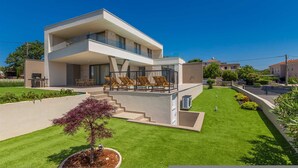 A modern two-story house with a flat roof, a balcony with outdoor seating, and a well-maintained lawn. - Villa Vista With Private Pool and Sauna (Krk)
