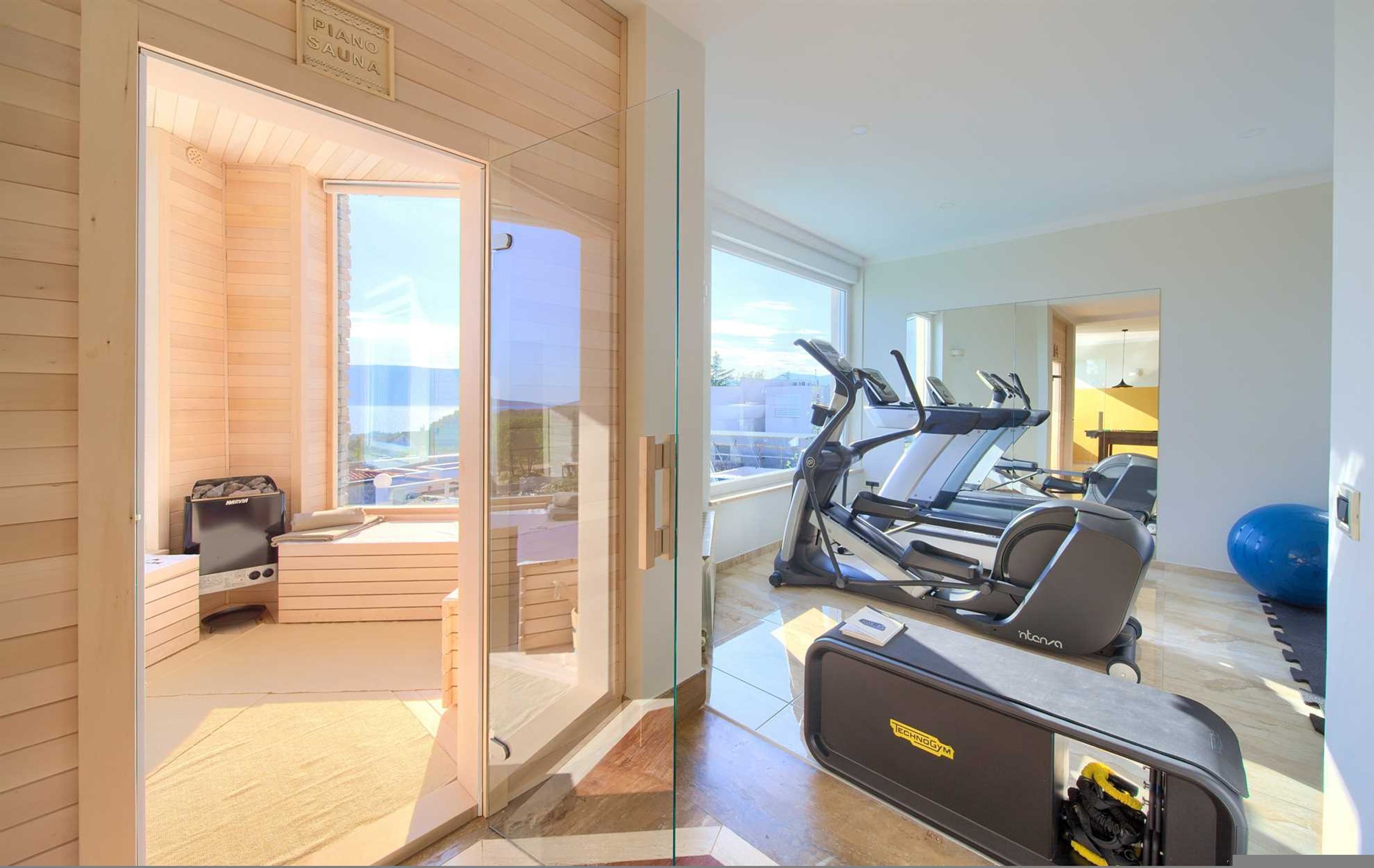 A modern gym with exercise equipment, a sauna, and a view of the city.