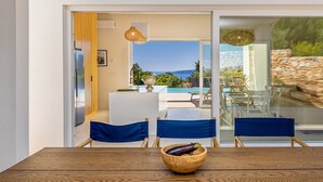 A dining area with a wooden table, blue chairs, and a bowl of fruit. - Villa Menta IV in Linardici (Krk)