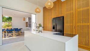 A modern kitchen with a white island, stainless steel appliances, and a wooden accent wall. - Villa Menta IV in Linardici (Krk)