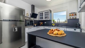 A modern kitchen with stainless steel appliances, a central island, and a window with a view. - Villa Katharina With Private Pool (Krk)