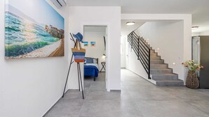 A modern interior with a staircase, a bed, and a large painting of a beach scene. - Villa Katharina With Private Pool (Krk)