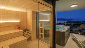 A sauna room with wooden benches, a glass door leading to a hot tub, and a balcony with a view. - Villa LEA Magdalena III (Krk)