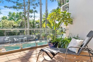 A balcony with a pool, outdoor seating, and potted plants.