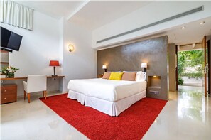 Relax in a spacious room with a large bed, desk, and wall-mounted TV, offering a view of the outdoors.