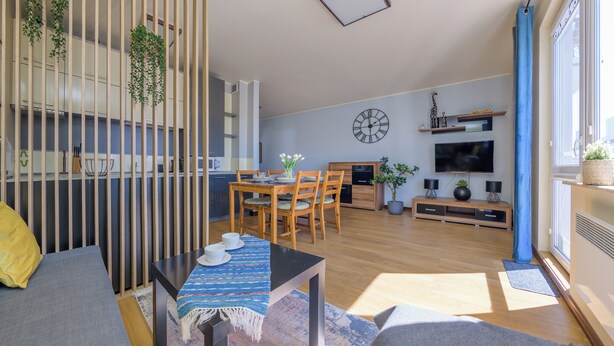 Un espacio moderno con comedor, cocina y un televisor grande.