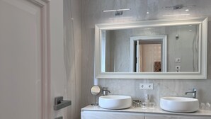 Ein modernes Badezimmer mit zwei Waschbecken, einem großen Spiegel und Holzboden.