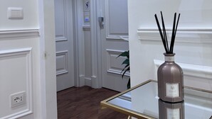 Ein Flur mit weißen Wänden, Holzboden und einem Glastisch mit einem Glas-Raumduft.