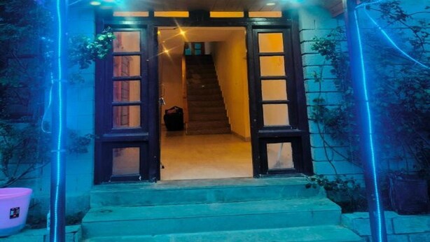 A wooden building with a porch and a staircase leading to an interior. - Arigato Cottage (Manali)